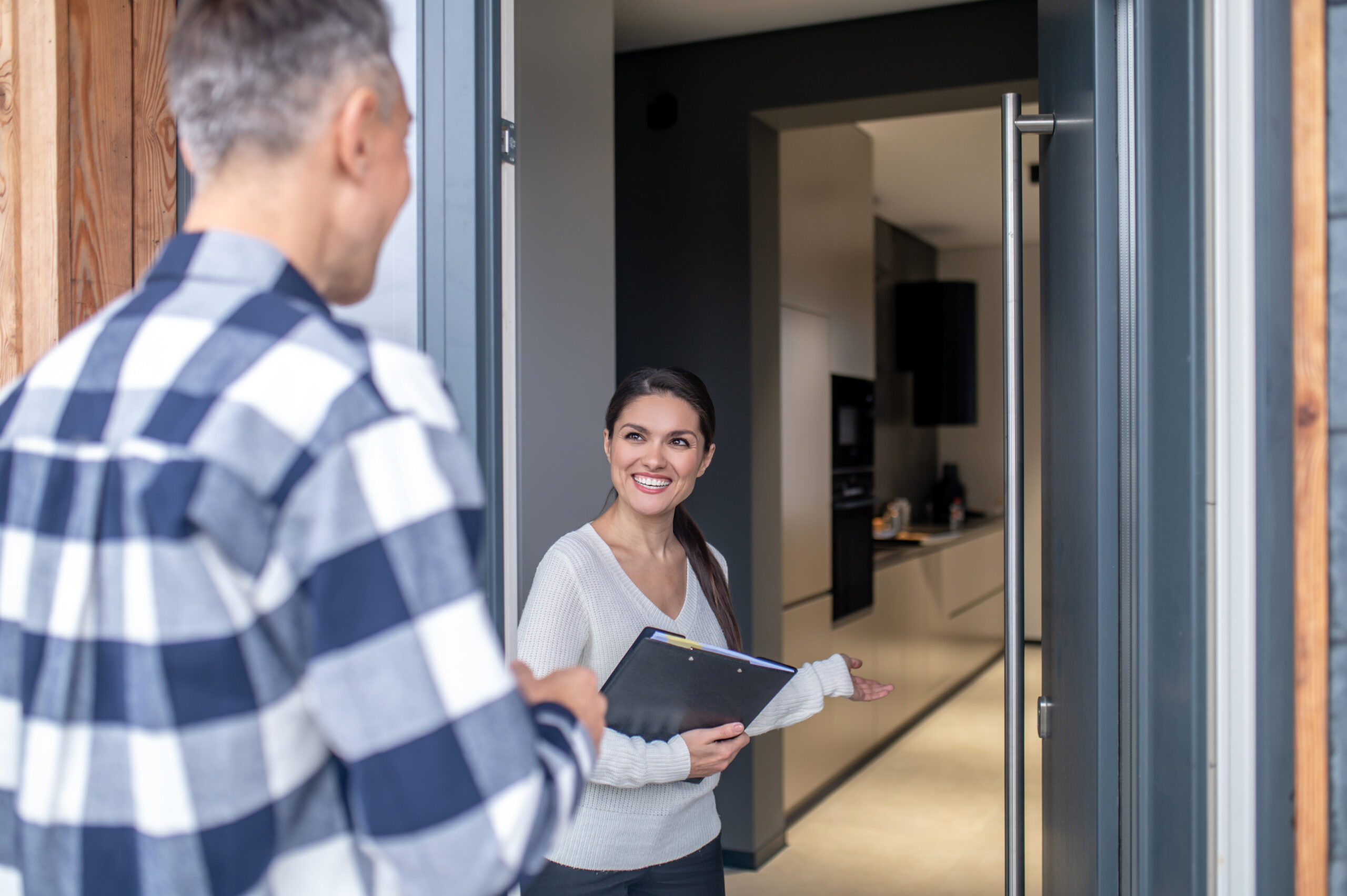 woman realtor standing near open door inviting man scaled